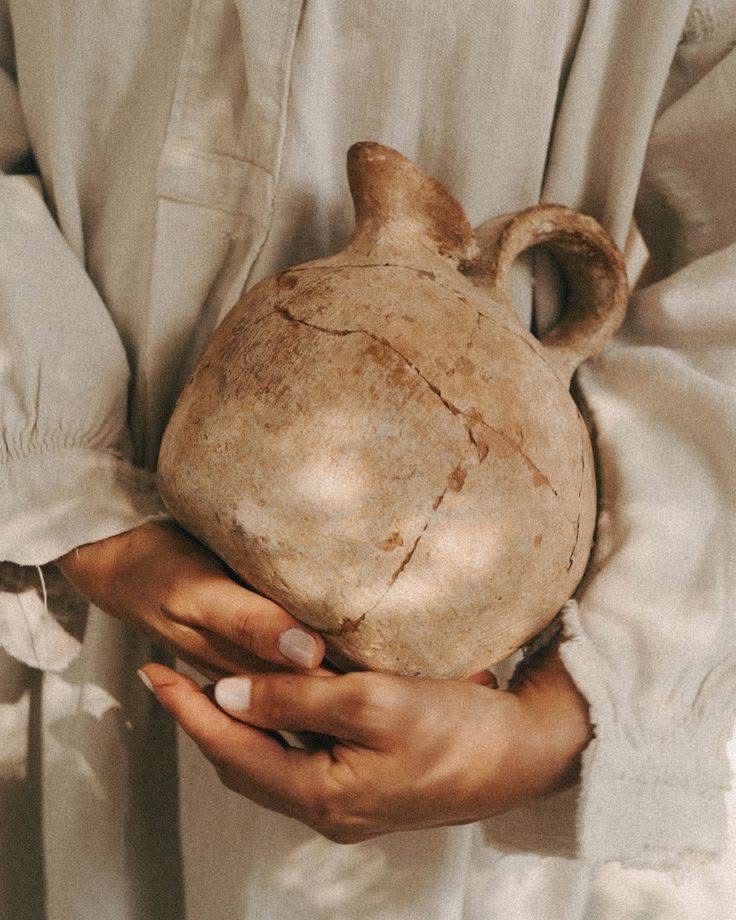 Hands cradling an aged earthen vessel